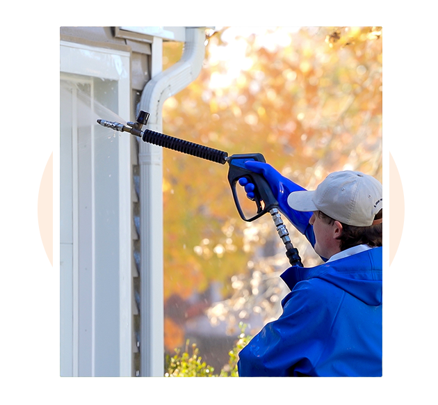 Professional pressure washing technician cleaning residential garage door in Exton PA — affordable, fully insured house washing and exterior cleaning service